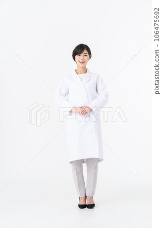 A young woman in a white coat standing against a white background A young woman in a white coat standing against a white background 106475692