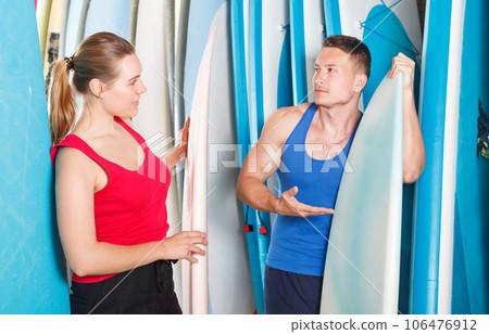 Surfers discussing while choosing boards and wetsuits Surfers discussing while choosing boards and wetsuits 106476912