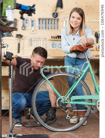 Man and woman pumping wheels of bicycle 106476946