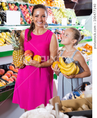 Cheerful young female with girl buying various fruits 106477140