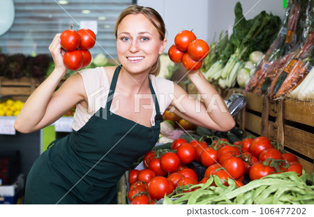 smiling young female seller holding fresh ripe tomatoes on market smiling young female seller holding fresh ripe tomatoes on market 106477202