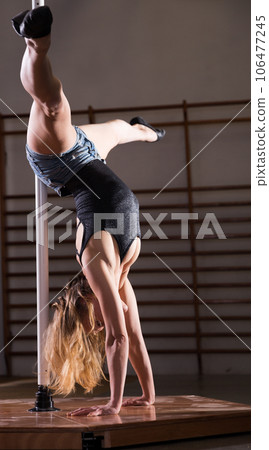 Young woman in denim shorts practicing pole dancing Young woman in denim shorts practicing pole dancing 106477245