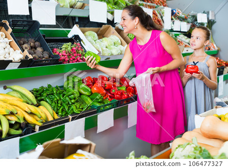 Mother with girl buying fresh peppers 106477327