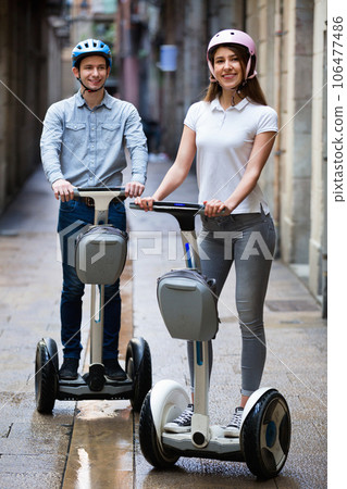 Positive boy and girl posing on segways in vacation Positive boy and girl posing on segways in vacation 106477486