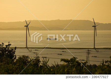 A wind turbine for wind power generation standing by the sea in the evening and receiving the sea breeze A wind turbine for wind power generation standing by the sea in the evening and receiving the sea breeze 106477827
