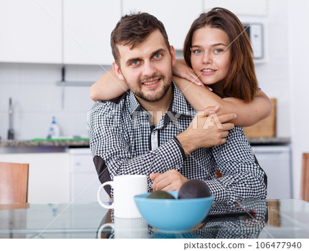 Smiling couple sitting at kitchen table and drinking tea at home Smiling couple sitting at kitchen table and drinking tea at home 106477940