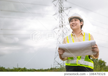 Happy engineer woman happy smiling with high voltages electricity transmission pole building project on background 106478328