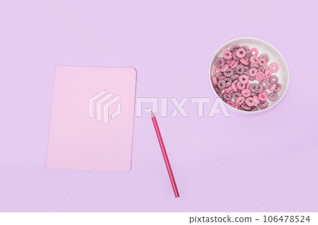Pink notebook with a pencil and corn flakes on a purple background, top view. Breakfast girls schoolgirls Pink notebook with a pencil and corn flakes on a purple background, top view. Breakfast girls schoolgirls 106478524
