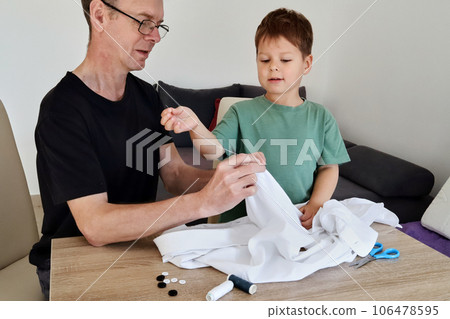 Father teaching his son how to sew on a button. Shot at home 106478595