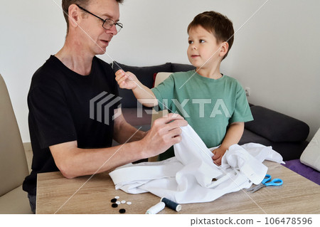 Father teaching his son how to sew on a button. Shot at home 106478596