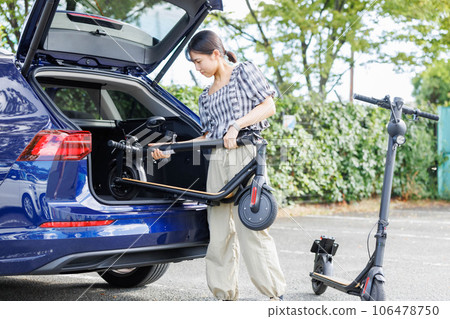 A woman putting an electric scooter on a car 106478750