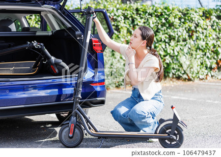 A woman putting an electric scooter on a car 106479437