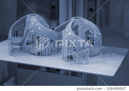 Printed models on 3D printer close-up. Objects printed on photopolymer sla 3D printer from liquid photopolymer resins on printing platform inside 3d printer. Modern progressive additive technology. 106480067