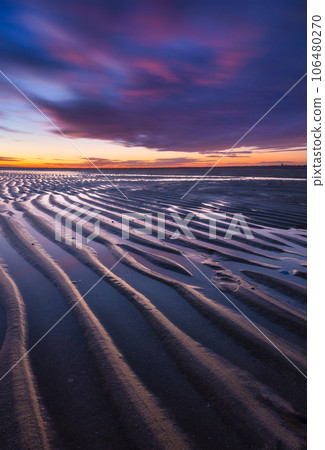 A seascape during sunset. Lines of sand on the seashore. Bright sky during sunset. A seascape during sunset. Lines of sand on the seashore. Bright sky during sunset. 106480270