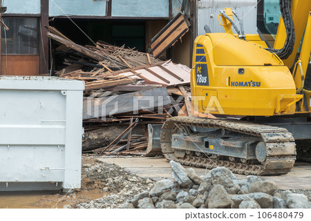 Demolition of a vacant house: heavy machinery, scrap wood, and buckets 106480479