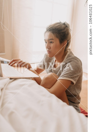Serious woman working with her laptop in the bedroom. Serious woman working with her laptop in the bedroom. 106481025