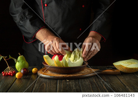 The chef sorts fruits on a plate for serving for dessert. The concept of a fruit diet in a restaurant kitchen. Asian national cuisine The chef sorts fruits on a plate for serving for dessert. The concept of a fruit diet in a restaurant kitchen. Asian national cuisine 106481143
