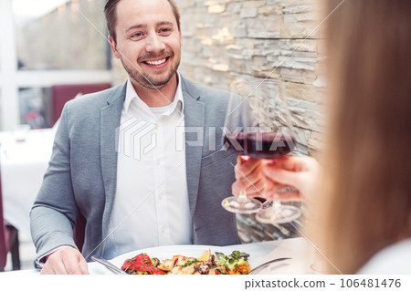 Man and woman enjoying a glass of red wine with their meal 106481476