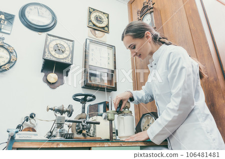 Woman watchmaker cleaning clockwork of a watch 106481481