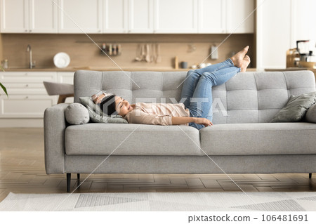 Peaceful relaxed young Indian woman resting on grey soft couch 106481691