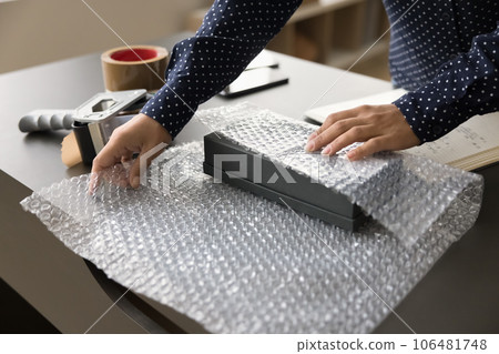 Hands of young female online shop employee wrapping black box 106481748