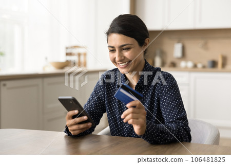 Happy satisfied young Indian woman finding account deposit Happy satisfied young Indian woman finding account deposit 106481825