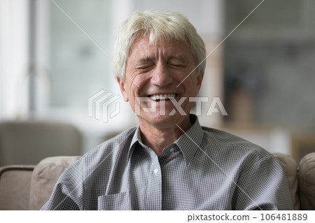 Cheerful mature old man laughing at camera with closed eyes 106481889