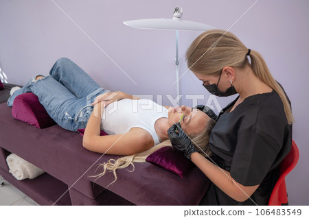 Caucasian woman on eyelash extension procedure. Caucasian woman on eyelash extension procedure. 106483549