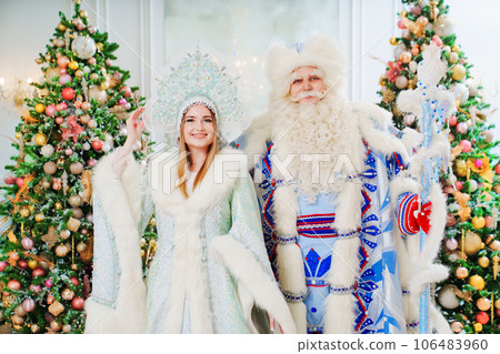 a Father Frost and Snow Maiden in blue costume in the room with christmas trees a Father Frost and Snow Maiden in blue costume in the room with christmas trees 106483960