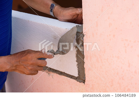 Bricklayer worker installing Lightweight Concrete on exterior wall with trowel putty knife. Bricklayer worker installing Lightweight Concrete on exterior wall with trowel putty knife. 106484189