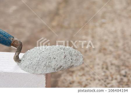 Cement powder or mortar with  trowel put on the Lightweight Concrete brick for construction work.. 106484194