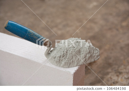 Cement powder or mortar with trowel put on the Lightweight Concrete brick for construction work.. Cement powder or mortar with trowel put on the Lightweight Concrete brick for construction work.. 106484198