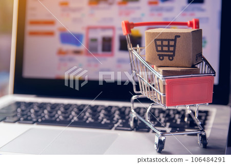 Shopping online concept - Parcel or Paper cartons with a shopping cart logo in a trolley on a laptop keyboard. Shopping service on The online web. offers home delivery.. Shopping online concept - Parcel or Paper cartons with a shopping cart logo in a trolley on a laptop keyboard. Shopping service on The online web. offers home delivery.. 106484291