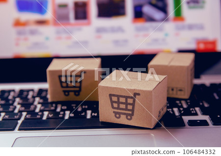 Online shopping - Paper cartons or parcel with a shopping cart logo on a laptop keyboard. Shopping service on The online web and offers home delivery.. Online shopping - Paper cartons or parcel with a shopping cart logo on a laptop keyboard. Shopping service on The online web and offers home delivery.. 106484332