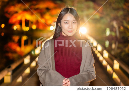 Young woman enjoying the illumination of autumn leaves 106485032