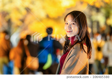 Young woman enjoying the illumination of autumn leaves 106485380