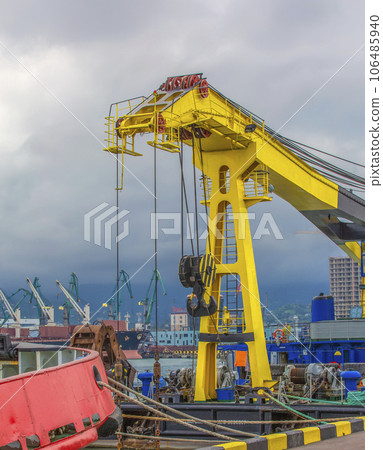 yellow sea lift against the background of cargo ships and a sky with clouds 106485940