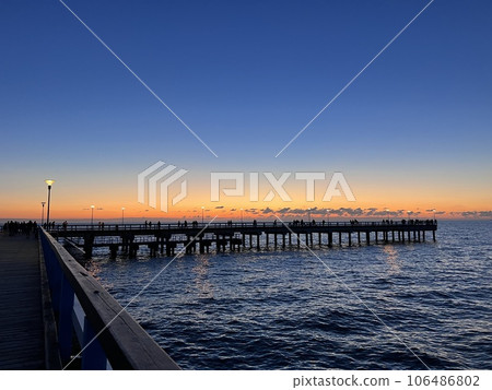 Palanga pier bridge with people resting against the background of the sea sunset Palanga pier bridge with people resting against the background of the sea sunset 106486802
