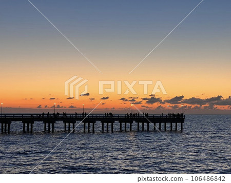 Palanga pier bridge with people resting against the background of the sea sunset Palanga pier bridge with people resting against the background of the sea sunset 106486842
