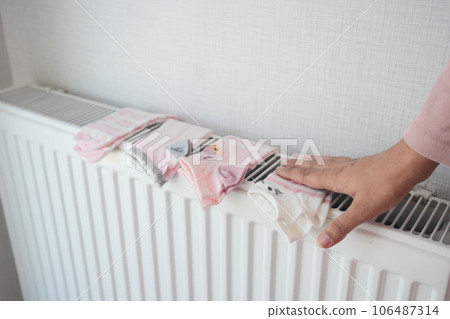 mother hand putting child socks on heating radiator to dry  106487314