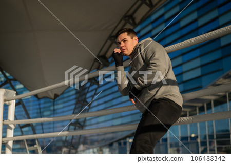 A man in a hoody trains in boxing at the stadium. A man in a hoody trains in boxing at the stadium. 106488342