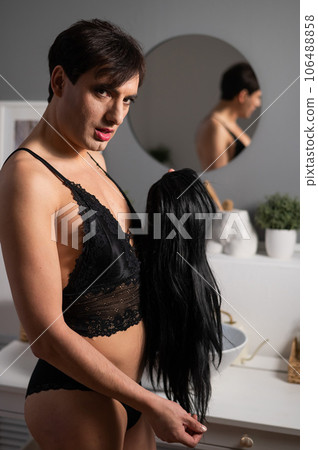 Homosexual preening in front of the mirror. A transgender man combing a wig. 106488858