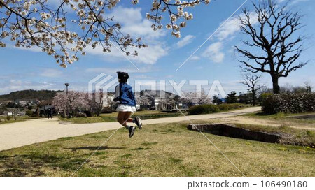一個女孩在櫻花盛開的公園裡玩耍 106490180