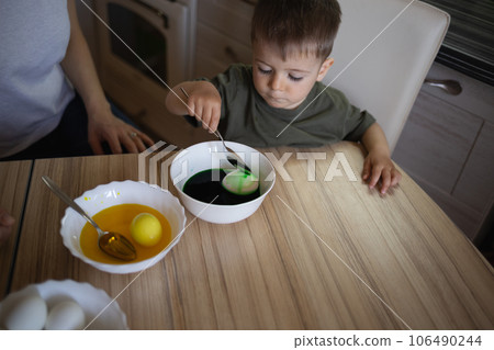 little cute boy paints eggs for easter sitting in the kitchen at the table little cute boy paints eggs for easter sitting in the kitchen at the table 106490244