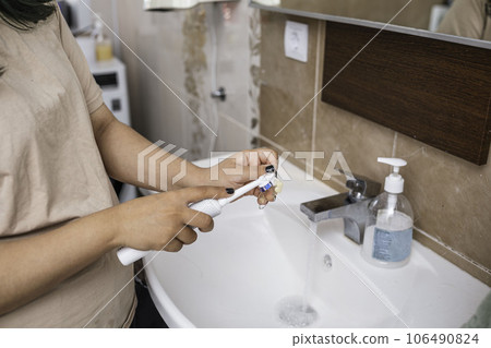 Cleaning of the teeth dentures in the sink with the running water and the toothbrush Cleaning of the teeth dentures in the sink with the running water and the toothbrush 106490824