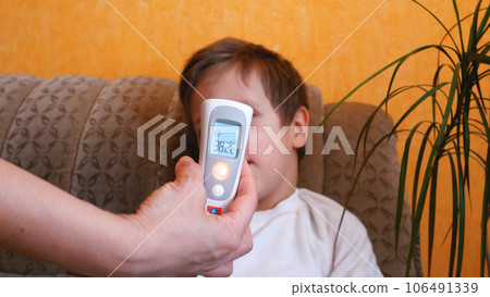 A woman's hand with an electronic thermometer measures the temperature of a child A woman's hand with an electronic thermometer measures the temperature of a child 106491339