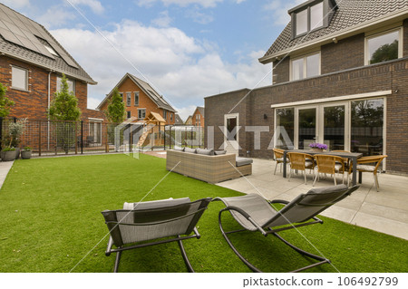 an outdoor living area with lawn and patio furniture in the middle part of the yard, surrounded by brick buildings 106492799