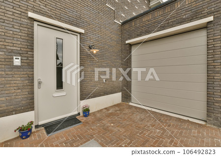 a brick house with two garage doors and one door open to the other side, in front of the house 106492823