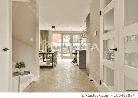 a hallway in a house with wood flooring and white trim on the walls there is an open door leading to another room 106492854