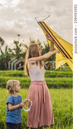 Mom and son launch a kite in a rice field in Ubud, Bali Island, Indonesia VERTICAL FORMAT for Instagram mobile story or stories size. Mobile wallpaper Mom and son launch a kite in a rice field in Ubud, Bali Island, Indonesia VERTICAL FORMAT for Instagram mobile story or stories size. Mobile wallpaper 106493992